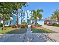 Two-story light blue house with palm trees, walkway, and well-maintained landscaping at 5112 Coastal Scene Dr, Apollo Beach, FL 33572