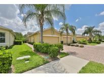 Tan house with palm trees and brick driveway at 806 Chipper Dr, Sun City Center, FL 33573