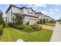 Two-story home with gray siding, landscaping, and a brick driveway at 4578 Emprise Way, Land O Lakes, FL 34638