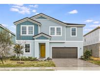 Two-story home with gray and blue siding, yellow door, and paved driveway at 10308 Fieldstone Mrytle Way, San Antonio, FL 33576