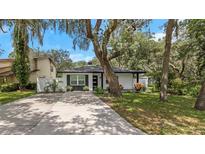 Modern house with a white exterior, landscaping, and a long driveway at 2221 S Village Ave, Tampa, FL 33612