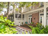 Relaxing patio with brick flooring and seating area, surrounded by lush greenery at 9 Pelican Pl, Belleair, FL 33756