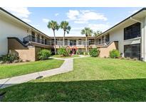 Two-story condo building with landscaped courtyard and walkway at 2700 Nebraska Ave # 4-103, Palm Harbor, FL 34684