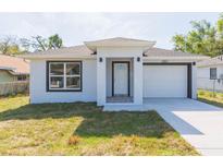 Charming home featuring a white exterior, well-manicured lawn, and an attached single car garage at 2911 E 20Th Ave, Tampa, FL 33605