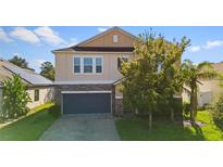 Two-story house with a stone and beige exterior, two-car garage, and landscaping at 3147 Calvano Dr, Land O Lakes, FL 34639