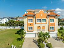 Stunning Mediterranean-style home featuring an eye-catching orange tile roof and a two-car garage, set against a clear blue sky at 136 175Th E Ave, Redington Shores, FL 33708