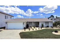 Updated single-story home with a stone facade, attached garage, and landscaped lawn at 9841 San Sebastian Way, Port Richey, FL 34668