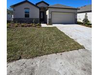 New construction home with two-car garage and landscaped lawn at 5152 Emerald Acres Way, Zephyrhills, FL 33541