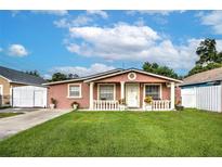 Pink stucco house with white columns and a well-maintained lawn at 6906 N Clark Ave, Tampa, FL 33614