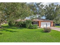 Charming single-story home features a well-maintained lawn, mature trees, and a welcoming front entrance at 3156 Depew Ave, Port Charlotte, FL 33952