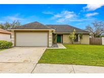 Tan house with a white garage door and green front door, featuring a well-maintained lawn at 651 Lakemont Dr, Brandon, FL 33510