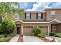 Tan two-story townhome with two-car garage and landscaping at 12820 Belvedere Song Way, Riverview, FL 33578