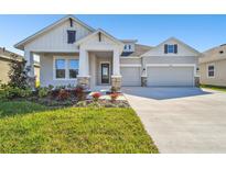 Two-story house with gray siding, stone accents, and a three-car garage at 6179 Hidden Branch Dr, Apollo Beach, FL 33572