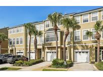 Charming townhomes with stucco exteriors, private garages, and mature palm tree landscaping under a clear blue sky at 2947 Bayshore Pointe Dr, Tampa, FL 33611