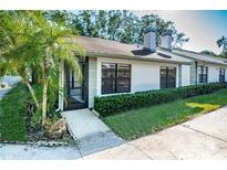 White exterior house with a screened porch and manicured hedges at 3508 Magnolia Ridge Cir # 301, Palm Harbor, FL 34684