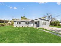 Charming gray home with a well-manicured lawn and front yard landscaping at 541 E Lime St, Tarpon Springs, FL 34689