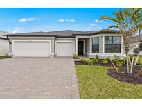Beautiful single-story home featuring a three-car garage and a well-manicured front yard and paver driveway at 2719 Winding Creek Trl, North Port, FL 34289