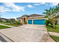 Two-story house with teal garage doors and landscaped yard at 5502 Limelight Dr, Apollo Beach, FL 33572