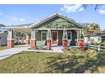 Green craftsman home with a covered porch and landscaped lawn at 1518 E Knollwood St, Tampa, FL 33610