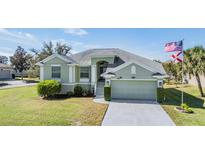 Charming single-story home features a well-manicured lawn, attached two-car garage, and neutral light-green exterior paint at 1002 Pondview Ct, Tarpon Springs, FL 34689
