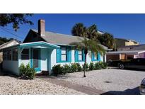 Charming light blue cottage with teal shutters and well-manicured landscaping at 130 E Bay Dr, Treasure Island, FL 33706