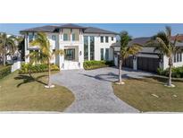 Stunning home showcasing a paver driveway, manicured lawn, tropical landscaping, and an attached three-car garage at 105 Cordova Ne Blvd, St Petersburg, FL 33704