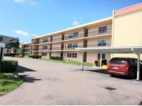 Three-story condo building with covered parking and balconies on each level, set against a sunny blue sky at 12200 Vonn Rd # 2106, Largo, FL 33774