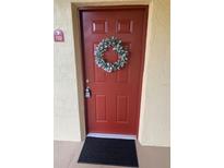 Welcoming red front door featuring a decorative wreath and unit number 722 at 2690 Coral Landings Blvd # 722, Palm Harbor, FL 34684