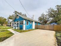 Charming blue home featuring a white brick chimney, wooden fence, and spacious driveway at 5205 N 9Th St, Tampa, FL 33603