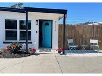 Charming front entrance features a vibrant blue door, manicured landscaping, and cozy outdoor seating at 9322 88Th Way, Seminole, FL 33777