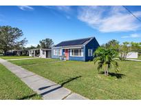 Blue house with solar panels, red door, and green lawn at 1001 57Th N Ave, St Petersburg, FL 33703