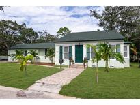 Charming, light green single-story home with a well-manicured lawn and a brick walkway leading to a green front door at 701 38Th N Ave, St Petersburg, FL 33704