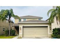 Tan two-story house with a two-car garage and landscaping at 2122 Richwood Pike Dr, Ruskin, FL 33570