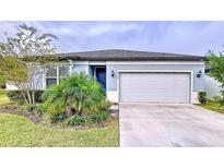 One-story home with gray garage door and blue exterior at 6119 Bradford Woods Dr, Zephyrhills, FL 33542