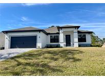 White house with gray accents, two-car garage, and well-manicured lawn at 5479 Brussels Ter, Port Charlotte, FL 33981