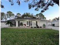 White house with green lawn, updated landscaping, and a paved driveway at 2353 Kilgore Dr, Largo, FL 33770