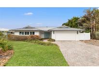 White house with gray metal roof, light blue door, and brick paver driveway at 10088 Paradise Blvd, Treasure Island, FL 33706