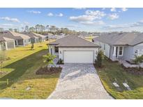 Single-story home with gray roof, white garage door, and landscaped yard at 9461 Shorebird Ct, Parrish, FL 34219