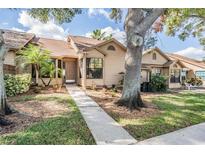 Tan house with walkway, landscaping, and mature trees at 2582 Bentley Dr, Palm Harbor, FL 34684