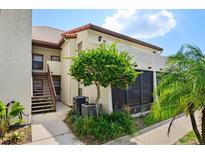 Charming two-story condo featuring a staircase, landscaping, and a stucco exterior, creating an inviting curb appeal at 2595 Cyprus Dr # 4-202, Palm Harbor, FL 34684