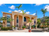 Two-story building with arched entryways, terracotta walls, and palm trees at 2691 Woodette Dr # D, Dunedin, FL 34698