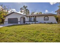 Modern home with a dark gray garage and white exterior at 4290 Yucatan Cir, Port Charlotte, FL 33948