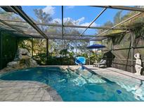 Inviting screened pool area with waterfall feature, lounge chairs, and basketball hoop at 4827 Queen Palm Ne Ter, St Petersburg, FL 33703