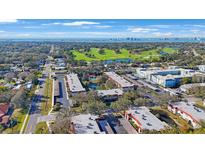 Panoramic aerial view of community, featuring a lush golf course, ponds, and distant city skyline at 1753 Belleair Forest Dr # E2, Belleair, FL 33756