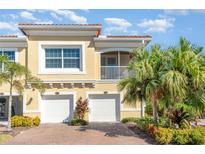 Tan two-story townhome with two-car garage, balcony, and lush landscaping at 4284 Expedition Way, Osprey, FL 34229