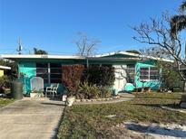 Charming teal ranch house with well-manicured lawn and walkway at 2485 Coronado Way, Dunedin, FL 34698