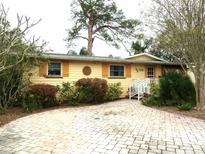 Cute yellow house with orange shutters, paved driveway and well-manicured landscaping at 1747 Douglas Ave, Dunedin, FL 34698