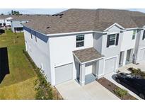 Two-story townhome with gray siding, attached garage, and driveway at 33055 Tulip Petal Ln, Wesley Chapel, FL 33545