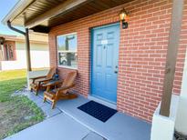 Inviting brick home exterior with a blue front door and wooden chairs on the porch at 24862 Us Highway 19 N # 3001, Clearwater, FL 33763