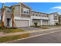 Three-unit townhome building with modern design, two-car garages, and landscaped yards at 3457 Timber Crossing Ave, Brandon, FL 33511